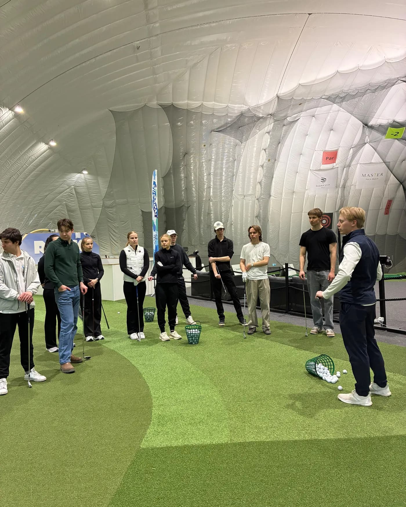 A Green Card course group listening to the instructor in the golf dome